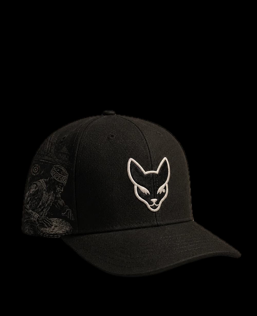 Black Xintu cap with bone-coloured cat embroidery and an illustrated drummer print on the side panel